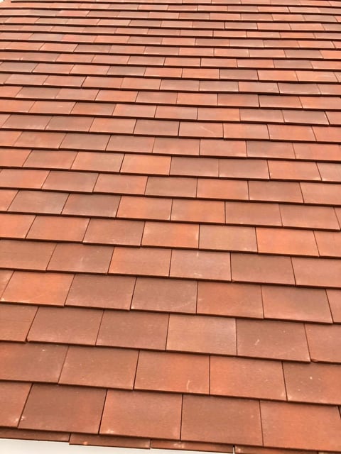 Close-up of terracotta roof tiles arranged in overlapping rows with shadows creating a textured pattern