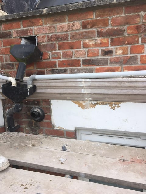 Black security camera mounted on red brick wall above a white window trim and concrete ledge