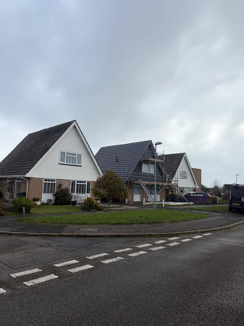 Row of residential houses with distinctive pitched roofs along a curved suburban street with gray overcast sky