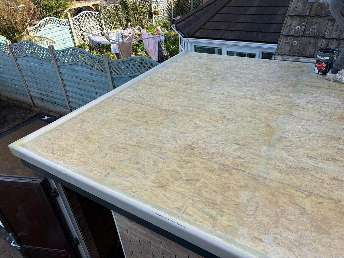 OSB plywood roof deck with white trim edge overlooking residential rooftops and garden area